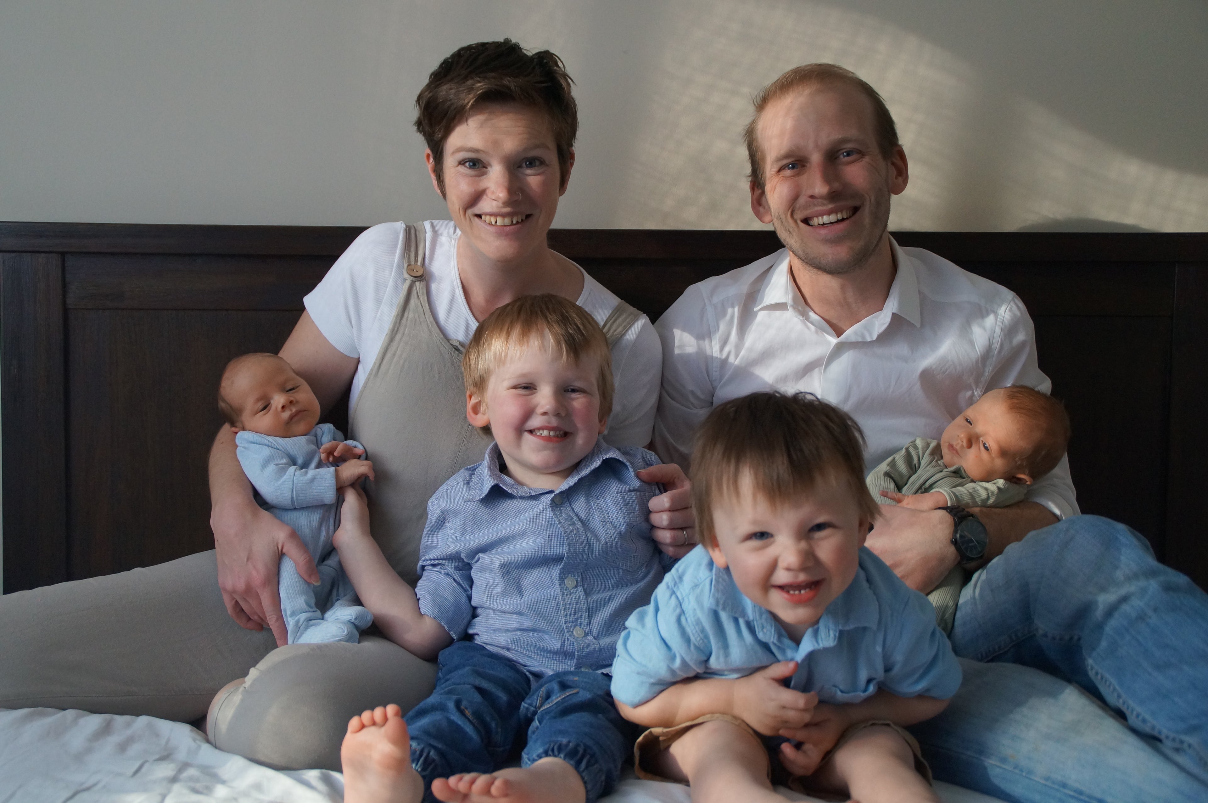 Colour family portrait photo of Hands Here founder with husband, two toddlers, and two babies all smiling