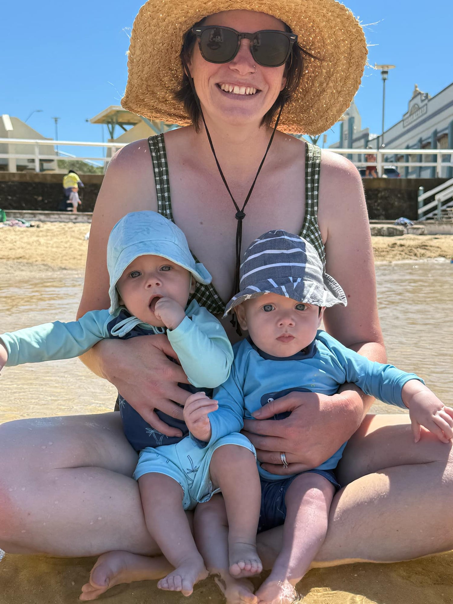 Colour image of Hands Here Founder sitting at the beach with her twins